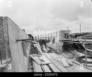 Ein Blick auf den Bau der Struktur 306 (Barn Bank Lane Bridge) auf der Birmingham to Preston Motorway (M6), der einen Arbeiter zeigt, der die Belastung des vorgespannten Betons ausführt. Diese Straßenbrücke, die sich an der SJ9211419999 befindet, wurde im März 1962 eröffnet. Stockfoto