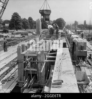Ein Blick auf den Bau der Autobahn Birmingham nach Preston (M6), der ein Team von Männern zeigt, die vor Ort einen der großen nachgespannten Balken auf der Brücke 306 (Barn Bank Lane Bridge) betonieren. Diese Straßenbrücke, die sich an der SJ9211419999 befindet, wurde im März 1962 eröffnet. Stockfoto