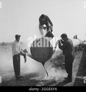 Ein Team von Mitarbeitern wickelte und versiegelte das Ende eines Stahlrohrs an der Fens-Gaspipeline. Die Arbeiten zur Verlegung der Fens-Gaspipeline begannen im Juni 1967 und waren ein Joint Venture zwischen Laing Civil Engineering und den französischen Unternehmen Entrepose und Grands Travaux de Marseille (GTM) für den Gasrat. Über 600 Männer arbeiteten an dem Projekt, Stahlrohre mit einem Durchmesser von 36 Zoll zu verlegen, beginnend bei West Winch in Norfolk, wo es mit dem nächsten Vertrag in Woodcroft Castle in Cambridgeshire in Verbindung gebracht wurde. Die Pipeline überquerte vier Flüsse und zahlreiche Deiche und Gräben. Stockfoto