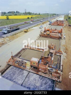 Verbreiterung der M1 in Hertfordshire mit Gleitschalungsmaschinen, die die Oberfläche einer neuen Straße entlang der bestehenden Fahrbahnen verlegen. Ab 1981 wurden an der M1 zwischen den Anschlussstellen 5 (South Watford) und der Anschlussstelle 8 (Hemel Hempstead) Verbreiterungen durchgeführt. Ziel war es, die bestehenden zweispurigen Fahrbahnen von den Kreuzungen 5 - 7 und die dreispurigen Fahrbahnen von den Kreuzungen 7 - 8 in drei Fahrspuren nach Süden, drei Fahrspuren nach Norden von den Kreuzungen 5 - 6 und vier Fahrspuren nach Norden von den Kreuzungen 6 - 8 umzuwandeln. Stockfoto