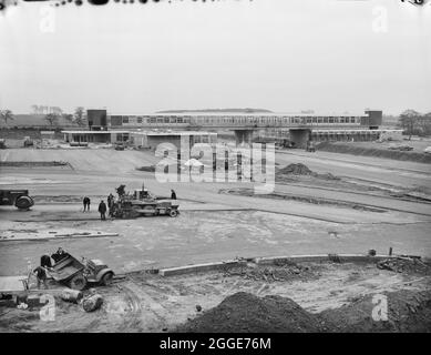 Ein Blick über das Keele Service Area während des Baus der Birmingham zur Preston Motorway (M6), zeigt ein Team von Arbeitern im Vordergrund, die auf Asphalt lagen. In dem Album heißt es unter dem Foto: „Diese Entwicklung, die von The Company for Motorway Services Limited durchgeführt wurde, besteht aus einem Hauptrestaurant über den Straßencafeterien und Transportcafés auf beiden Seiten der Autobahn. Dies ist eine viel verbesserte Version von der in Newport Pagnell.' Stockfoto