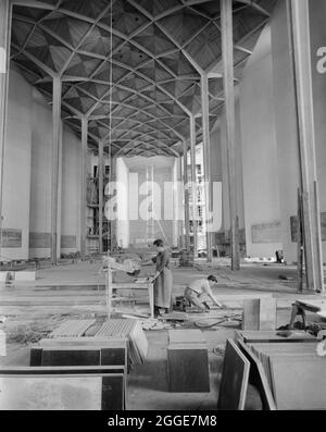 Blick vom Kirchenschiff auf den Chor in der Kathedrale von Coventry während des Baus, mit zwei Männern im Vordergrund, die am Boden arbeiteten. Dieses Bild wurde als Teil des Breaking New Ground Project in Zusammenarbeit mit dem John Laing Charitable Trust in den Jahren 2019-20 katalogisiert. Stockfoto