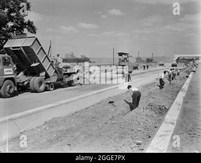 Baumaschinen, die in Abschnitt D4 der London to Yorkshire Motorway (M1) einen trockenen Betonboden legen, während die Arbeiter von Laing im Vordergrund einen Graben für die zentrale Reservationsentwässerung graben. Der Abschnitt D der Autobahn London-Yorkshire verläuft zwischen Kislingbury und Dunchurch. Die Beschriftung unter dem entsprechenden Albumdruck weist darauf hin, dass die Straße östlich von Struktur 113 verlegt wird. Stockfoto