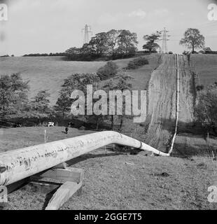 Ein Blick entlang eines Teiles der Mersey-Ölpipeline in hügeligen Landschaften, der die Pipeline zeigt, nachdem die Schweißer vorbeigegangen sind, aber bevor die Fugen beschichtet wurden. Die Mersey-Ölpipeline wurde 1967 von Laing Civil Engineering in Zusammenarbeit mit den französischen Unternehmen Entrepose und Grands Trevaux de Marseille (GTM) installiert. Es ist 88 Meilen lang und verläuft vom Ellesmere Port zum Kingsbury Oil Terminal, das die Midlands bedient. Dieses Foto wurde im November 1967 im monatlichen Newsletter „Team Spirit“ von Laing veröffentlicht. Stockfoto