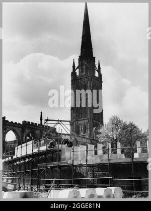 Ein Blick auf drei Bauherren, die an einem Teil des Tauffensters der Kathedrale von Coventry arbeiten, mit einigen Steinen, die zum Fenster im Vordergrund gehören, und im Hintergrund dem Turm der alten Kathedrale. Dieses Bild wurde als Teil des Breaking New Ground Project in Zusammenarbeit mit dem John Laing Charitable Trust in den Jahren 2019-20 katalogisiert. Stockfoto