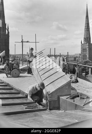 Zwei Männer, die während des Baus der Kathedrale von Coventry an einem Kupferdach arbeiteten. Dieses Bild wurde als Teil des Breaking New Ground Project in Zusammenarbeit mit dem John Laing Charitable Trust in den Jahren 2019-20 katalogisiert. Stockfoto