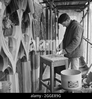 Ein Steinmetz, der in der Kathedrale von Carlisle arbeitet, bereitet die Vermaschung eines Fensters für den neuen Stein vor, der von SBD Certite gehalten werden soll. Dieses Foto ist Teil einer Charge, die von Laing aufgenommen wurde, um Restaurierungsarbeiten zu zeigen, die mit SBD Certite durchgeführt werden. 1961 begann N M Phillips, der Architekt der Kathedrale von Carlisle, bei der Restaurierung der Kathedrale mit dem Bindematerial SBD Certite zu experimentieren. Es wurde an allen, bis auf eines der dekorierten gotischen Fenster des Südlichen Gotteshauses verwendet und als dieses Foto aufgenommen wurde, wurde es bei der Restaurierung der Nordwand der Kathedrale verwendet. Durch die Verwendung von SB Stockfoto