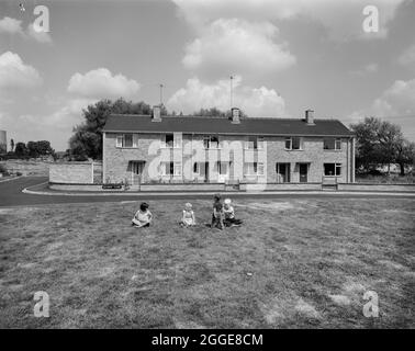 Eine Gruppe von Kindern, die auf dem Gras vor einer Reihe von Easiform-Reihenhäusern auf Sundaw Close spielen. „Easiform“ war eine Methode der in situ vorgegossenen Betonkonstruktion, die John Laing und Son Ltd ab 1919 entwickelten. Stockfoto