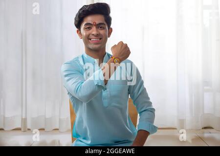 EIN FRÖHLICHER TEENAGER, DER RAKHI VOR DER KAMERA ZEIGT Stockfoto