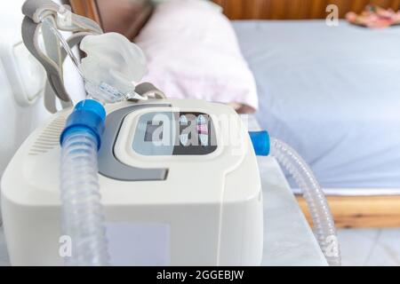 CPAP-Gerät mit Luftschlauch und Kopfmaske auf Nachttisch Stockfoto