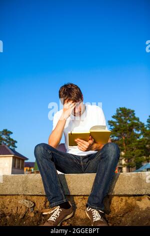 Unruhigen jungen Mann las ein Buch draußen Stockfoto