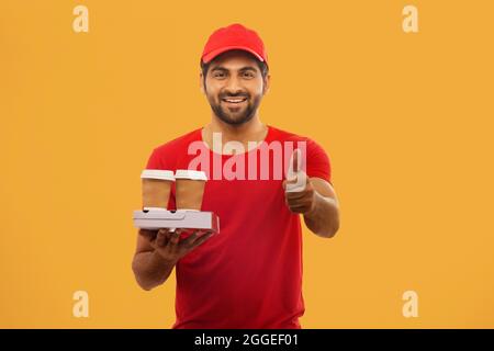 EIN GLÜCKLICHER LIEFERER, DER MIT VERPACKTEN LEBENSMITTELN STAND Stockfoto