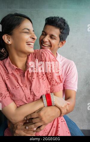 Junge glückliche frisch Vermählte verbringen eine schöne Zeit, während die Frau auf dem Schoß des Ehemannes sitzt. Stockfoto