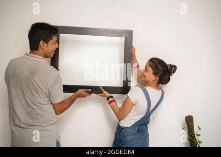 Junge Jungvermählte schmücken die Wand ihres neuen Hauses. Stockfoto