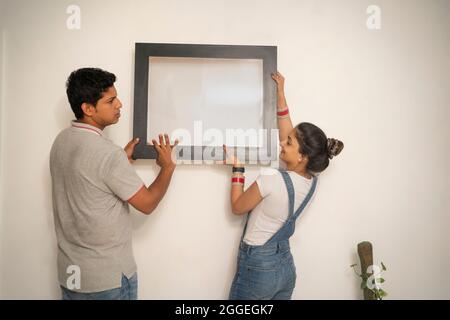 Junge Jungvermählte schmücken die Wand ihres neuen Hauses. Stockfoto