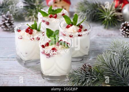 Weisser weihnachtlicher Mojito aus Likör, Tequila, Kokosmilch mit Granatapfelkernen, Kokosflocken und erfrischender Minze. Stockfoto