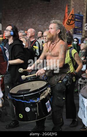 London Bridge Station, London, Großbritannien. August 2021. Aktivisten von Extinction Rebellion (XR)-Gruppen marschieren mit Transparenten, Plakaten und Musikinstrumenten durch den Bahnhof London Bridge im Zentrum Londons, bevor sie die Rolltreppen in einen Zug nehmen. Kredit: Imageplotter/Alamy Live Nachrichten Stockfoto