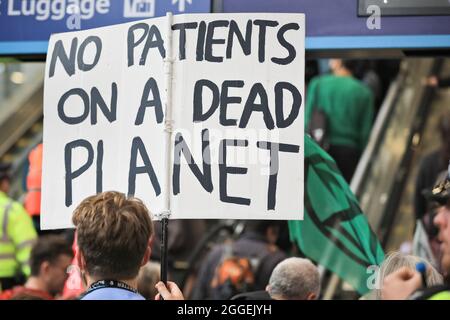 London Bridge Station, London, Großbritannien. August 2021. Aktivisten von Extinction Rebellion (XR)-Gruppen marschieren mit Transparenten, Plakaten und Musikinstrumenten durch den Bahnhof London Bridge im Zentrum Londons, bevor sie die Rolltreppen in einen Zug nehmen. Kredit: Imageplotter/Alamy Live Nachrichten Stockfoto