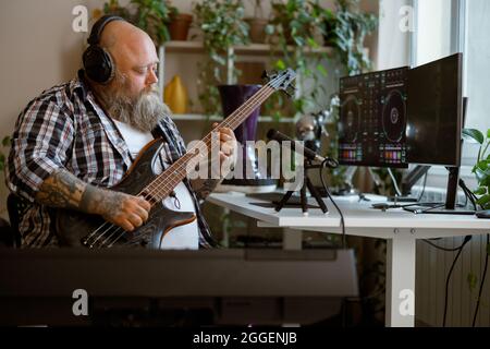 Konzentrierter Musiker spielt Basgitarre Aufnahme Song im Heimstudio Stockfoto