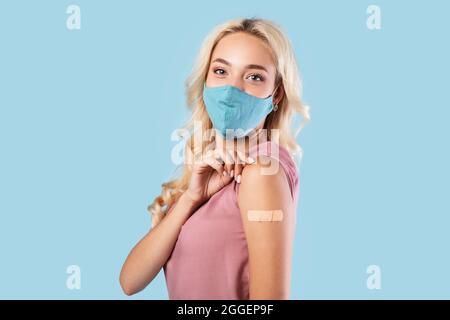 Werbung Für Die Impfung Gegen Coronaviren. Glücklich Geimpfte Dame In Stoff Gesichtsmaske Zeigt Arm Mit Klebstoff Gipsverband Nach Covid-19 Injektion Sh Stockfoto