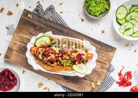 Gesunder vegetarischer Hot Dog mit Fladenbrot aus Gemüse, garniert mit roten Zwiebeln, Gurken und Erbsenpüree Stockfoto
