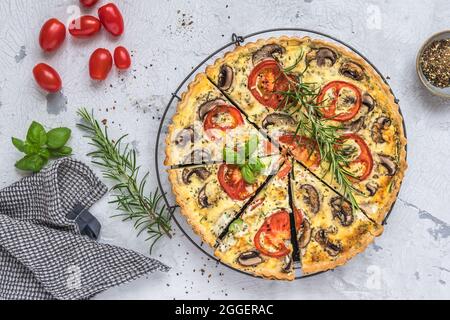 Ganze hausgemachte Gemüsetorte mit Pilzen, Tomaten und Zucchini auf weißem Hintergrund, Draufsicht Stockfoto