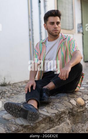 Ein hübscher Kaukasier mit gestreiftem Hemd, der auf der Straße posiert Stockfoto