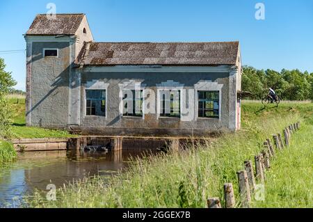 Region Königsberg, Russland, 13. Juni 2021. Das Gebäude ist eine Pumpstation. Technisches Gebäude am Ufer. Das graue Haus am Fluss. Alt ruiniert Stockfoto