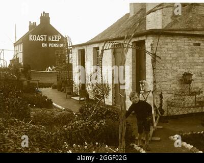 Vintage Fred C Palmer Fotografie - Koast Keep - kleiner Junge mit Schaukelpferd vor den Gebäuden. Stockfoto