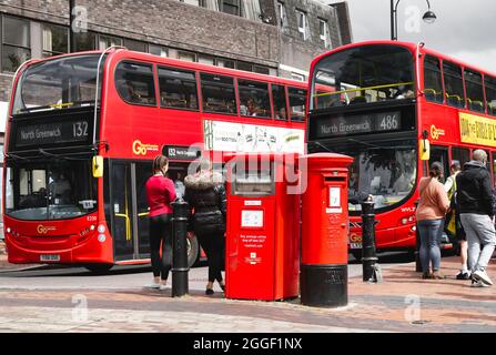 Bexleyheath Kent England 08.31.21 zwei rote Londoner Busse fahren an einer Straße vorbei. Königliche Briefkästen und Paketkassetten. Leute warten darauf, an Bord der Öffentlichkeit zu gehen Stockfoto
