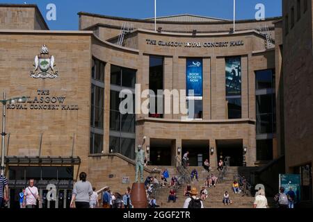 Die Menschen genießen den Sonnenschein auf den Stufen hinter der Donald Dewar-Statue vor der Royal Concert Hall, Buchanan Street, Glasgow City Centre, Schottland, UK Stockfoto
