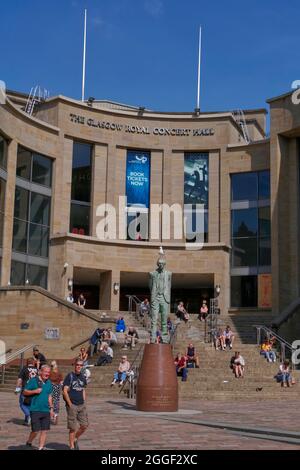 Die Menschen genießen den Sonnenschein auf den Stufen hinter der Donald Dewar-Statue vor der Royal Concert Hall, Buchanan Street, Glasgow City Centre, Schottland, UK Stockfoto