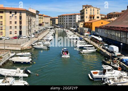 Blick von oben auf einen Kanal im Viertel New Venice mit Booten, die an den Docks und dem Fischmarkt-Gebäude auf der rechten Seite, Livorno, Toskana, festgemacht sind Stockfoto