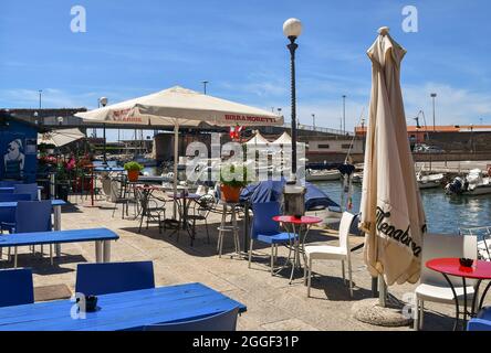 Eine Außenfassade mit Blick auf den Kanalhafen des Viertels New Venice mit festfahrenden Booten im Sommer, Livorno, Toskana, Italien. cafè Stockfoto