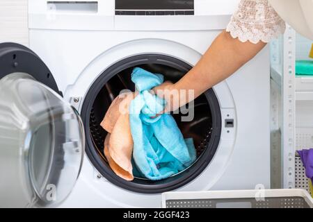 Ältere asiatische Frau, die Handtuchwäsche in die Waschküche einlädt Stockfoto