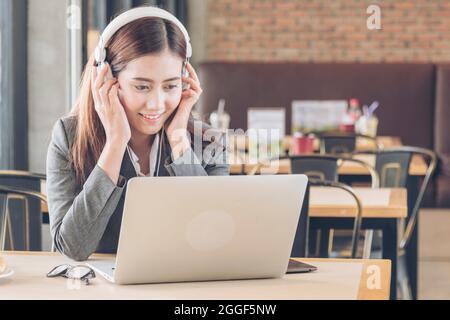 Junge schöne Call Center-Agent mit Headset und Laptop kommunizieren mit Kunden. Support Call Center Helpline mit lächelndem Gesicht und Service Stockfoto