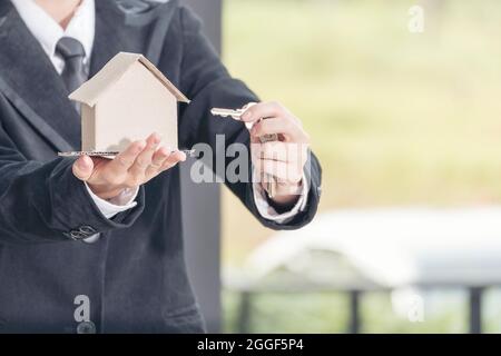 Immobilienmakler zeigt neues Haus und Banknote aus Sparkonto für die Hausversicherung. Immobilien-Konzept Stockfoto