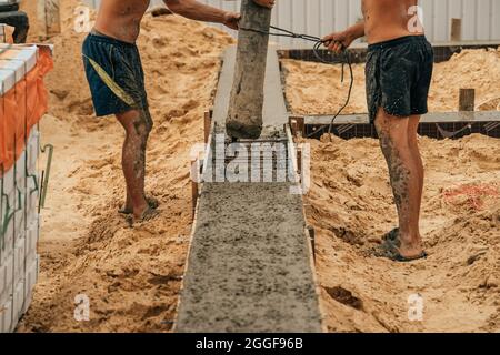 Gießen von Zement oder Beton mit automatischer Pumpe, Baustelle mit verstärktem Gitter-Fundament, Beginn des neuen Hausbaus. Stockfoto