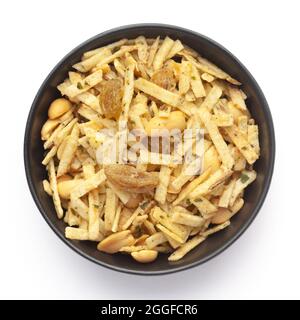 Nahaufnahme der Aloo-Mischung in einer schwarzen Keramikschale mit Kartoffeln, Erdnüssen, Rosinen. Indische, würzige Snacks (Namkeen), Blick von oben Stockfoto