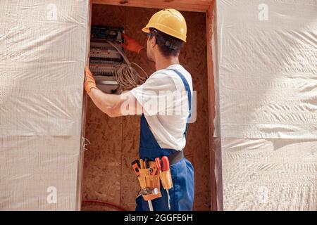 Männlicher Baumeister, der den elektrischen Zähler in der Baukabine überprüft Stockfoto