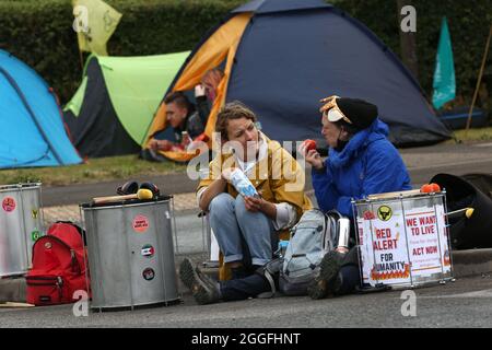 Aylesbury, Großbritannien. August 2021. Demonstranten, die ein Gespräch führten, als 50 Animal Rebels Arlas Hauptmilchfabrik in Aylesbury stillgelegt haben, indem sie den Eingang mit Leuchttürmen, Rebellen und Fahrzeugen blockierten. Die Rebellen wollen eine Verpflichtung von Arla, die Milchproduktion zu beenden und bis 2025 vollständig pflanzenbasiert zu sein, um das Leid von Milliarden von Menschenleben zu beenden und die Klimakrise abzuwenden. Kredit: SOPA Images Limited/Alamy Live Nachrichten Stockfoto