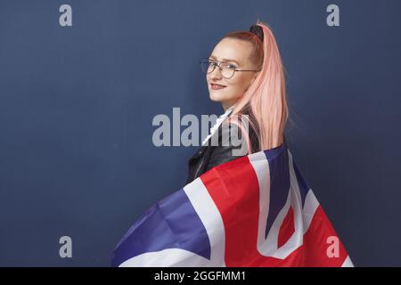 Junge Frau Expat in Brillen mit Großbritannien Flagge. Studioaufnahme. Hipster-Lehrerin in englischer Sprache Stockfoto