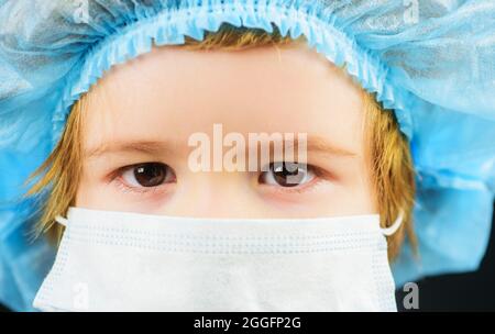 Kind in Maske zum Schutz vor einer Coronavirus-Pandemie des Covid-19. Prävention von Krankheiten. Kleiner Junge mit medizinischer Kappe und Maske. Nahaufnahme. Stockfoto