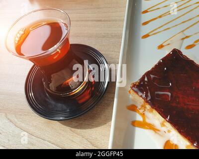 Türkischer Tee und Tres leches Kuchen auch bekannt als Trilece mit Karamell in einem Teller auf dem Tisch. Berühmte köstliche Milchdessert des Balkans. Stockfoto