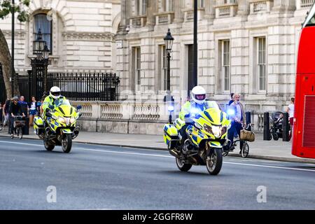 London, England - 2021. August: Polizisten auf Motorrädern mit blauen Lichtern fahren eine Straße im Zentrum Londons entlang Stockfoto