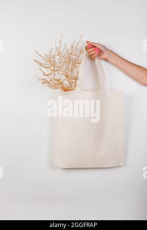 Hochwertige Premium-Stofftasche aus Canvas. Mockup White Tasche auf weißem isolierten Hintergrund mit Zweig der getrockneten Blumen für Text oder Design, Konzept der gemacht Stockfoto