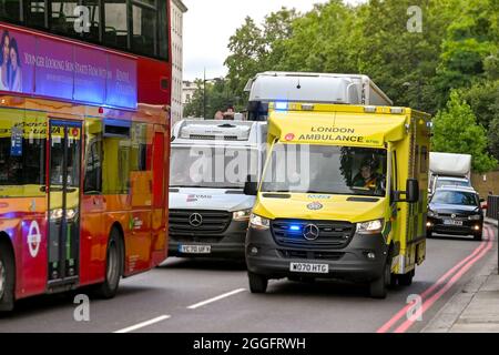 London, England - 2021. August: Londoner Krankenwagen mit blauen Ampeln, die als Reaktion auf einen Notruf durch den Verkehr im Zentrum Londons fahren. Stockfoto