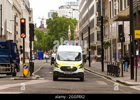 London, England - 2021. August: Polizeiwagen mit blauen Lichtern, die eine Straße im Zentrum Londons entlang fahren Stockfoto