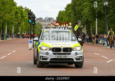 London, England - 2021. August: Polizei patrouilliert Auto eskortiert Soldaten auf dem Pferderücken die Mall hinunter. Stockfoto