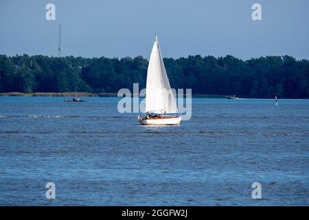 Helsinki / Finnland - 31. AUGUST 2021: Ein kleines Segelboot, das über den Horizont segelt. Stockfoto